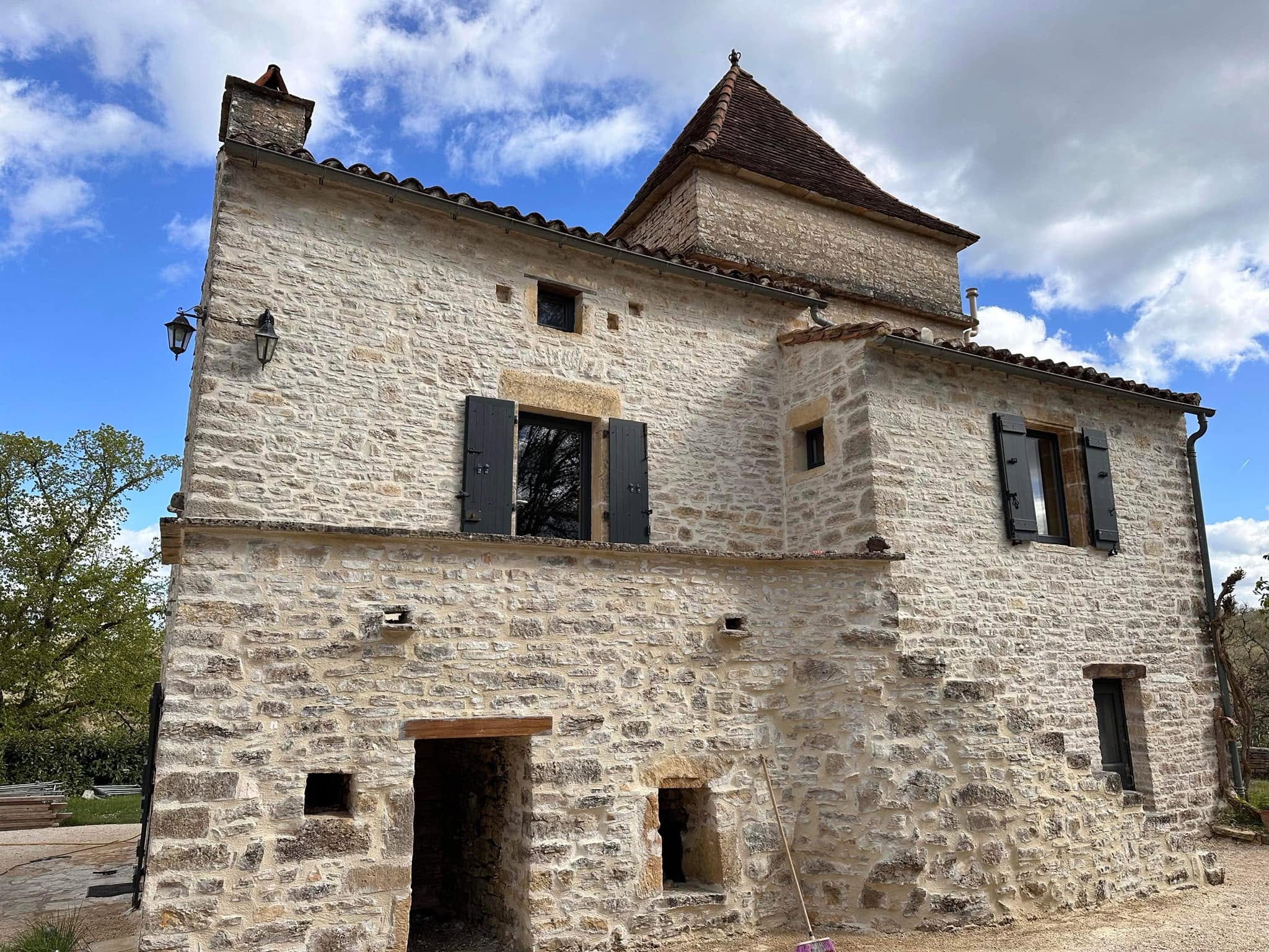 Bâtisse de caractère en pierre claire, restaurée, avec une tour et des volets gris