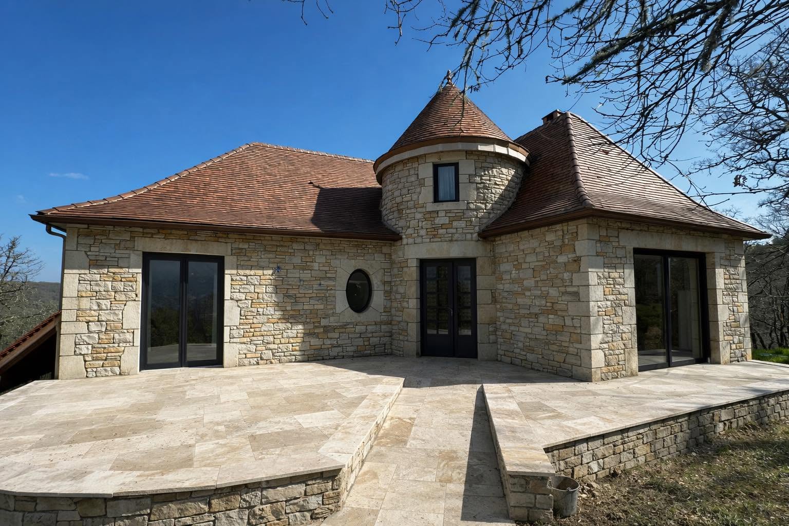 Maison en pierre avec tour et terrasse dallée